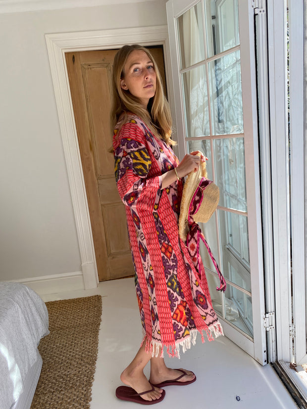 Woman in a colorful dress holding a hat indoors. Oversized Beach Shirt Dress - Watermelon Pink Ikat iridescent sea Fremantle, Perth