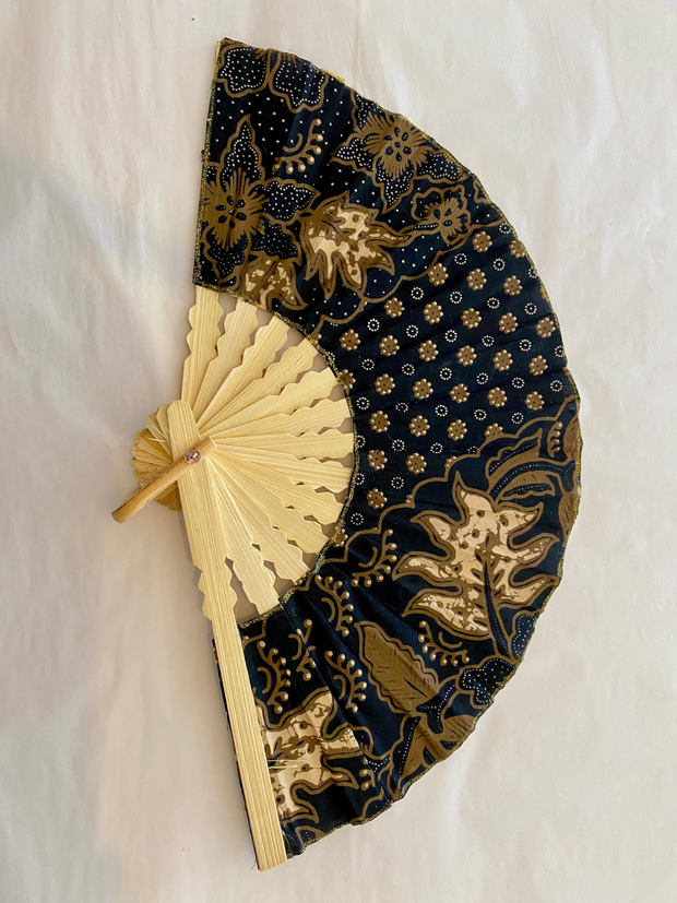 Handheld fan with black and gold floral pattern on a white background