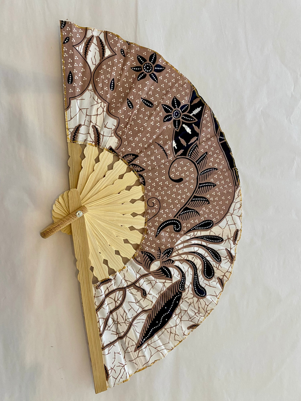 Decorative hand fan with intricate patterns on a light background