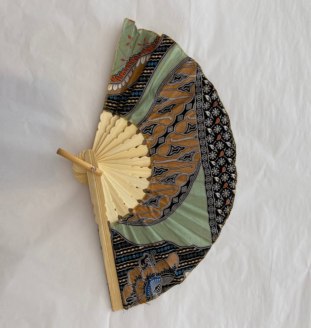 Decorative hand fan with patterned fabric cover on a white background