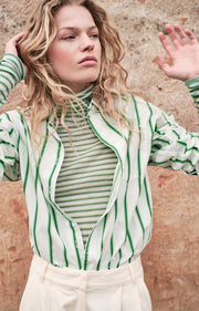 Woman wearing a green and white striped shirt with a textured wall background AMERICAN VINTAGE Zatybay Shirt in Neon Lagoon Stripes Iridescent Sea Fremantle Perth