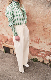 Woman wearing a green and white striped shirt with a textured wall background AMERICAN VINTAGE Zatybay Shirt in Neon Lagoon Stripes Iridescent Sea Fremantle Perth