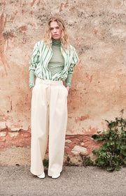 Woman wearing a green and white striped shirt with a textured wall background AMERICAN VINTAGE Zatybay Shirt in Neon Lagoon Stripes Iridescent Sea Fremantle Perth
