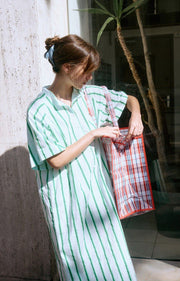 Woman wearing a green and white striped dress standing in front of a building entrance. AMERICAN VINTAGE Zatybay Dress in Neon Lagoon Stripes Iridescent sea Fremantle Perth