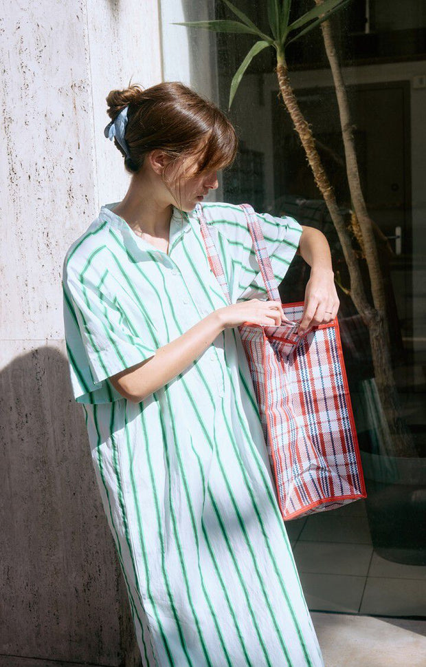 Woman wearing a green and white striped dress standing in front of a building entrance. AMERICAN VINTAGE Zatybay Dress in Neon Lagoon Stripes Iridescent sea Fremantle Perth