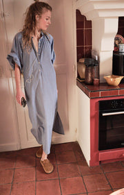 Woman in a blue dress standing in a kitchen with a red oven. AMERICAN VINTAGE Zatybay Dress in Aqua Stripes Iridescent Sea Fremantle Perth